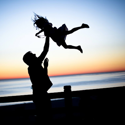 Silhouette of adult and child playing at a beach