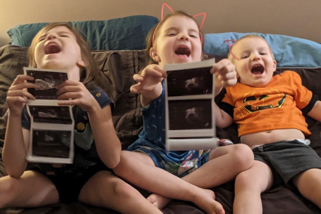 children holding ultrasound pictures and laughing