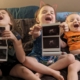 children holding ultrasound pictures and laughing