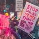 Woman marches with a sign that reads "Stop calling violence feminism"