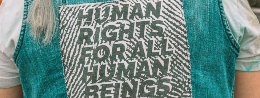 A woman wearing a denim vest with a human rights message on it
