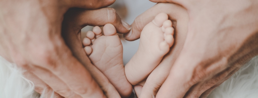 Adult hands cradle a baby's feet