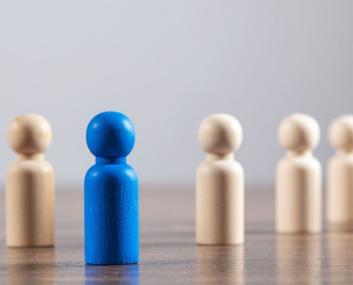 Blue Wooden Figure Standing Out From Crowd